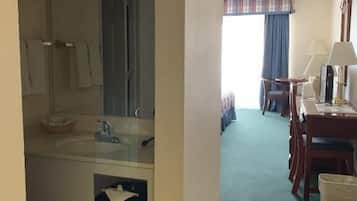 Una habitación de hotel con baño, zona de comedor y vistas al exterior.