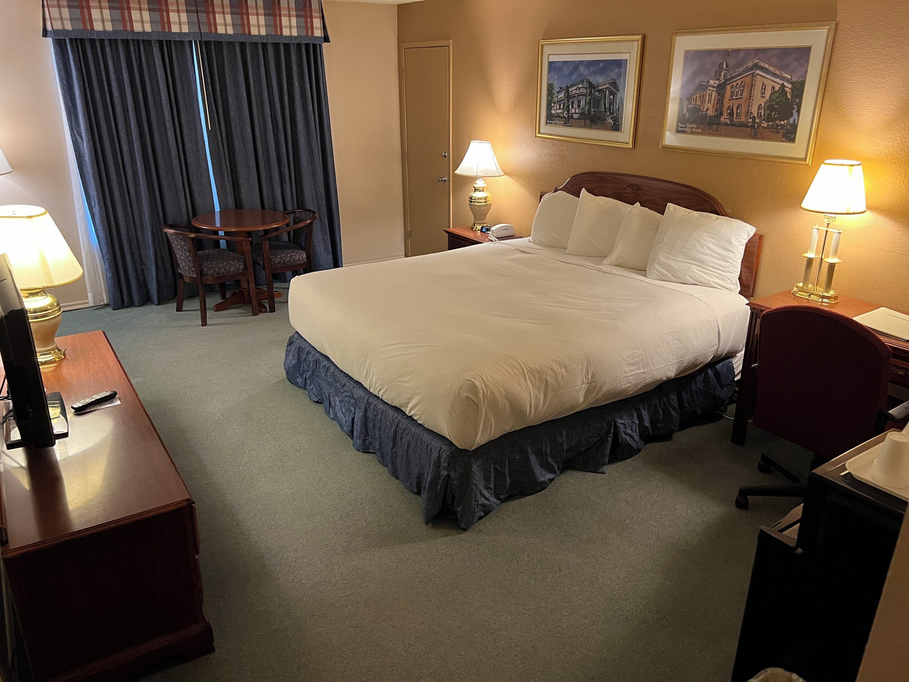 Ein Hotelzimmer mit einem großen Bett, einem Schreibtisch, einem Stuhl, einem Fernseher und zwei Lampen.