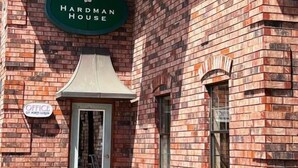 A brick building with a sign reading "Hardman House." - Hardman House Inn & Suites (Carson City)
