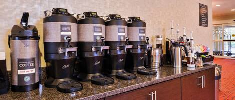 Una estación de café con varios dispensadores de café y un dispensador de agua caliente.