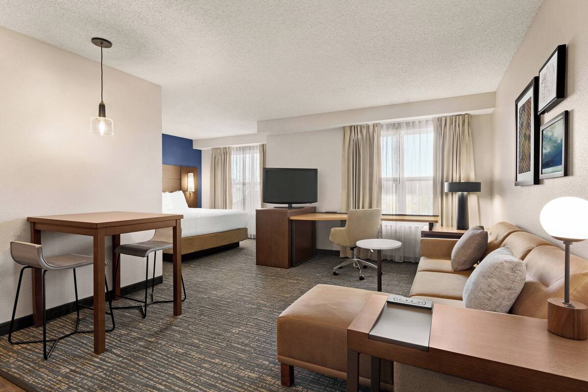 A hotel room with a bed, desk, sofa, and a TV.