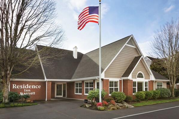 Un bâtiment en briques, orné d’un mât où flotte un drapeau, une enseigne indiquant « Residence Inn Marriott » et une pelouse bien entretenue.