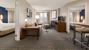 Ein Hotelzimmer mit einem Bett, einem Schlafsofa, einem Schreibtisch, einem Sessel, einem Fernseher und einem Kamin.