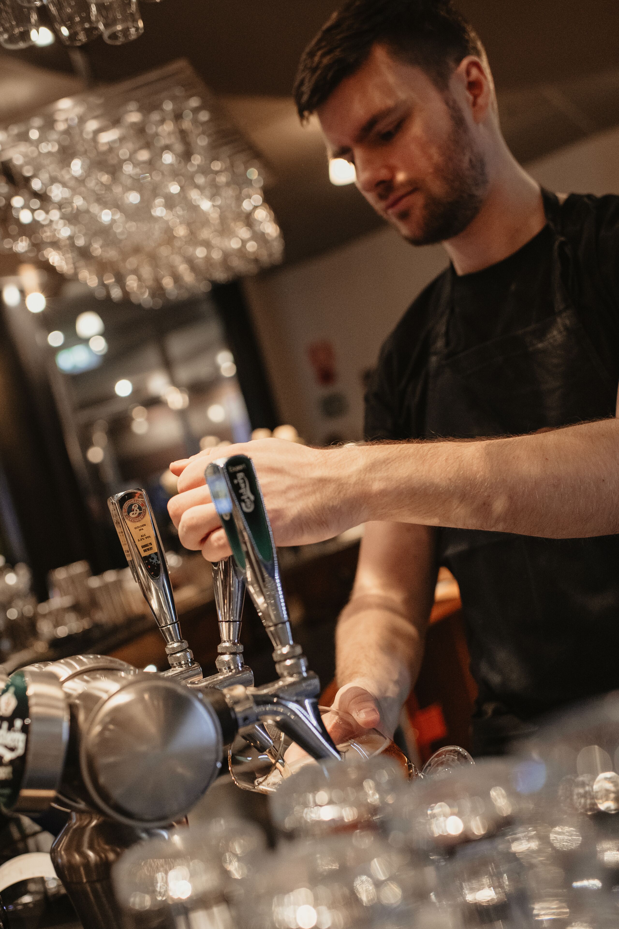 A person operating a tap in a bar setting.