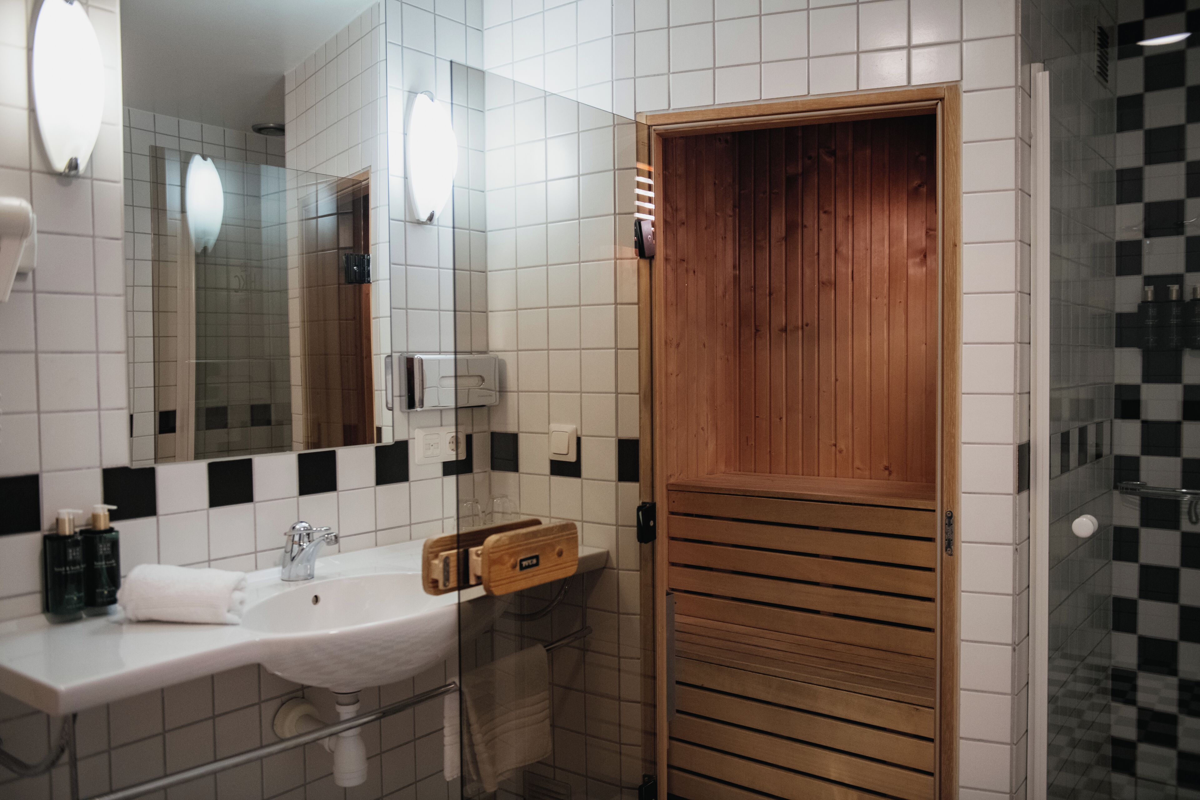 A bathroom with a white sink, mirror, and wooden door.