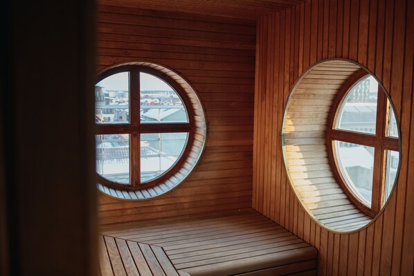 A room with wooden walls and a bench, featuring two large circular windows with a cross design.