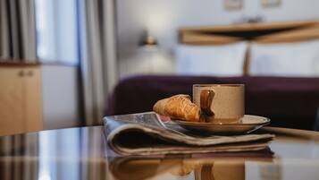 Una mesa con una taza de café, un croissant y un periódico.