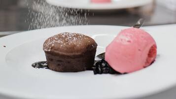 En desserttallrik med en chokladmuffin och en skopa rosa glass, beströdd med florsocker.