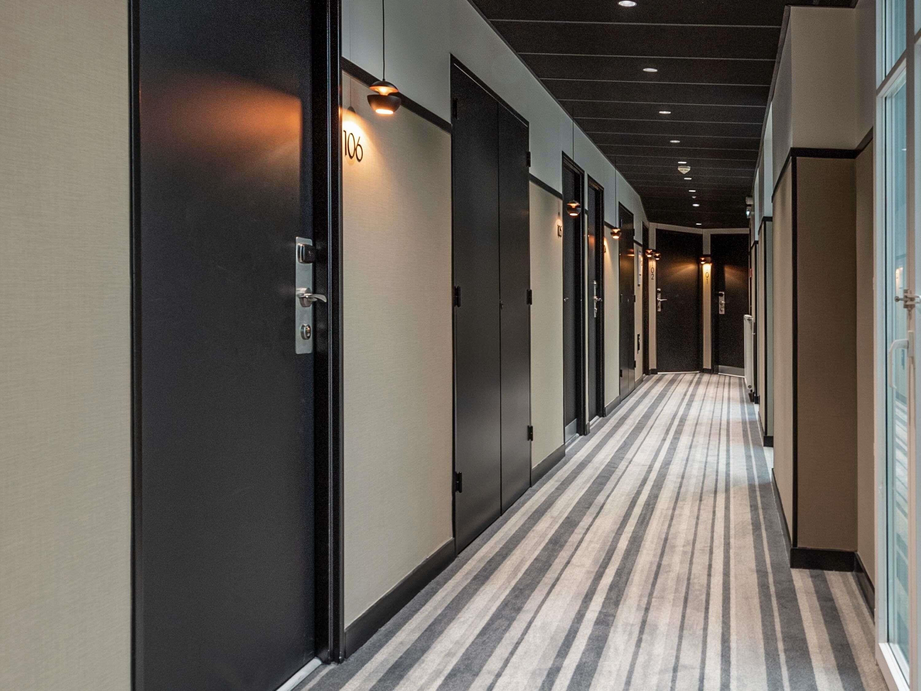 A hotel corridor with doors numbered 106 and 102, carpeted floors, and recessed lighting.