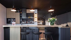 A modern kitchen with a central island, bar stools, and a wine rack. - Mercure St Malo Front De Mer (Saint-Malo)