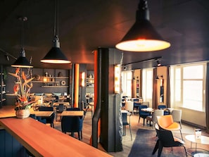 Ein modernes Café mit Holztischen, schwarzen Stühlen und Pendelleuchten.