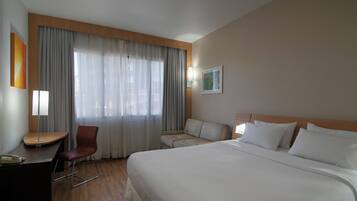 A hotel room with a bed, a desk, a chair, and a sofa.