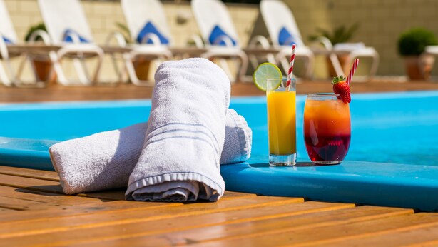 A poolside setting with lounge chairs, a towel, and two drinks. - Novotel Porto Alegre Tres Figueiras Hotel (Porto Alegre)