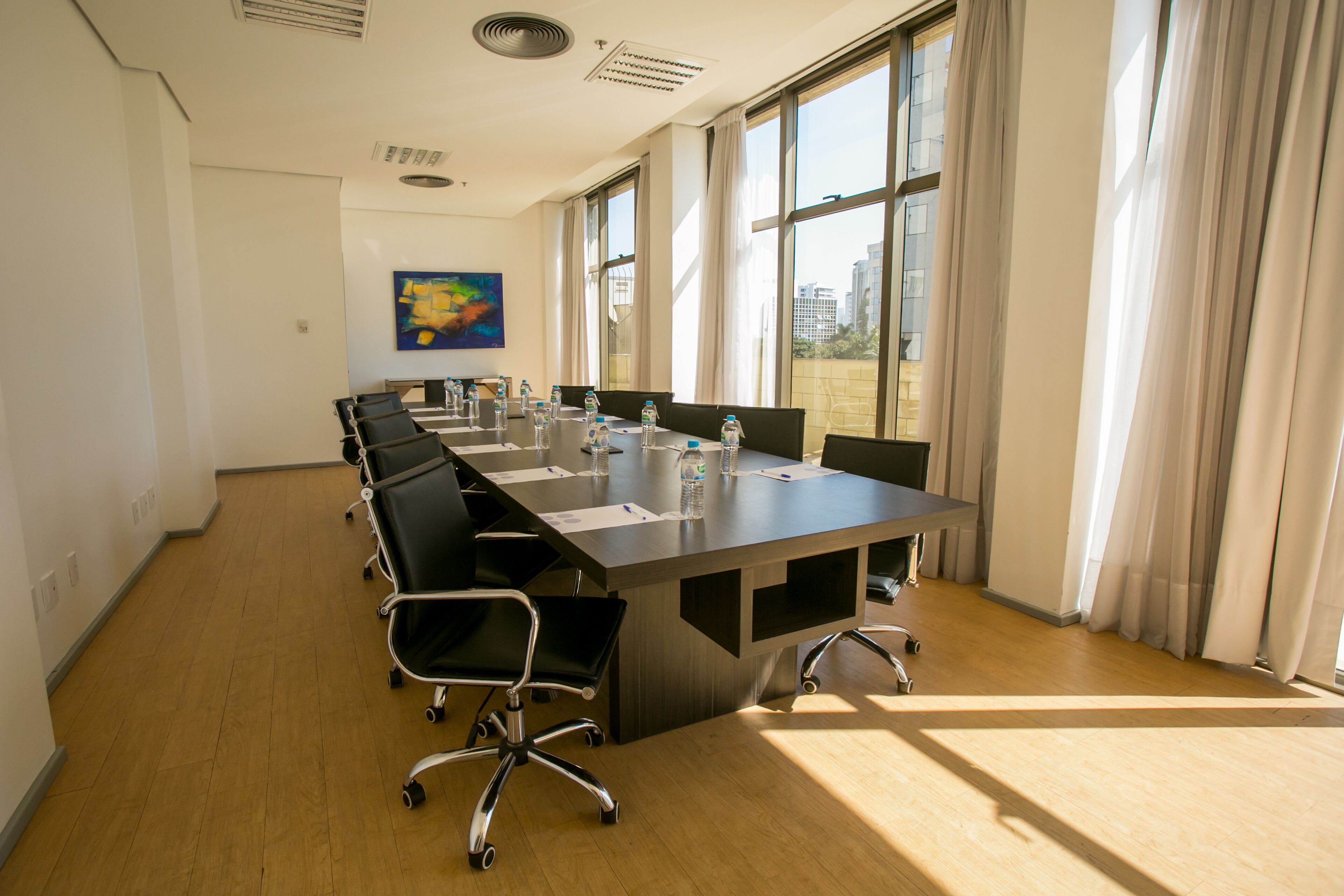 A conference room with a long table, chairs, and large windows.