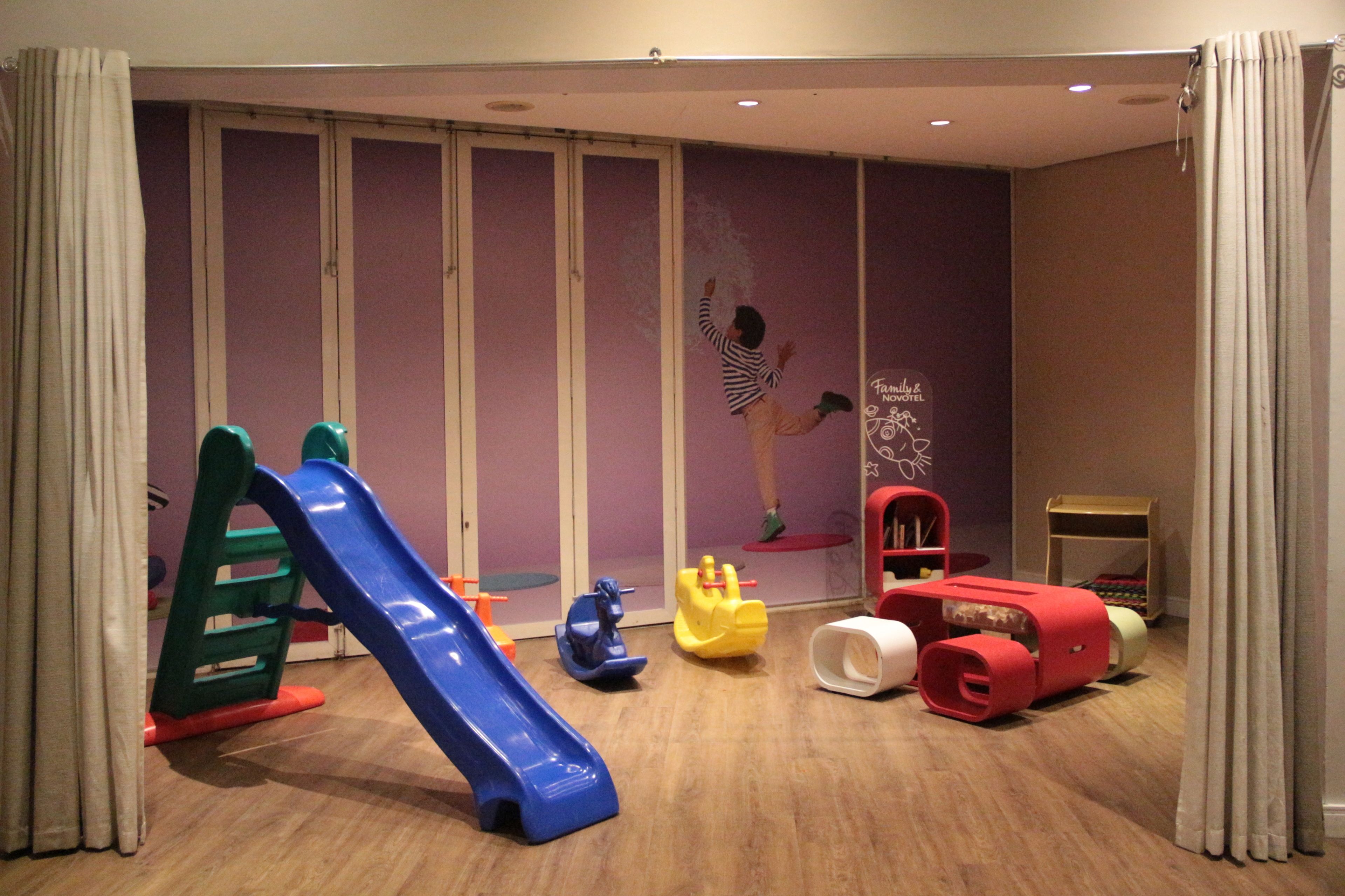 A children's play area with a blue slide, various toys, and a wall with a poster.