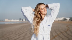 A person in a white robe standing on a sandy beach with a clear sky in the background. - Le Médina Essaouira Thalassa Sea  & Spa - MGallery Collection (Essaouira)