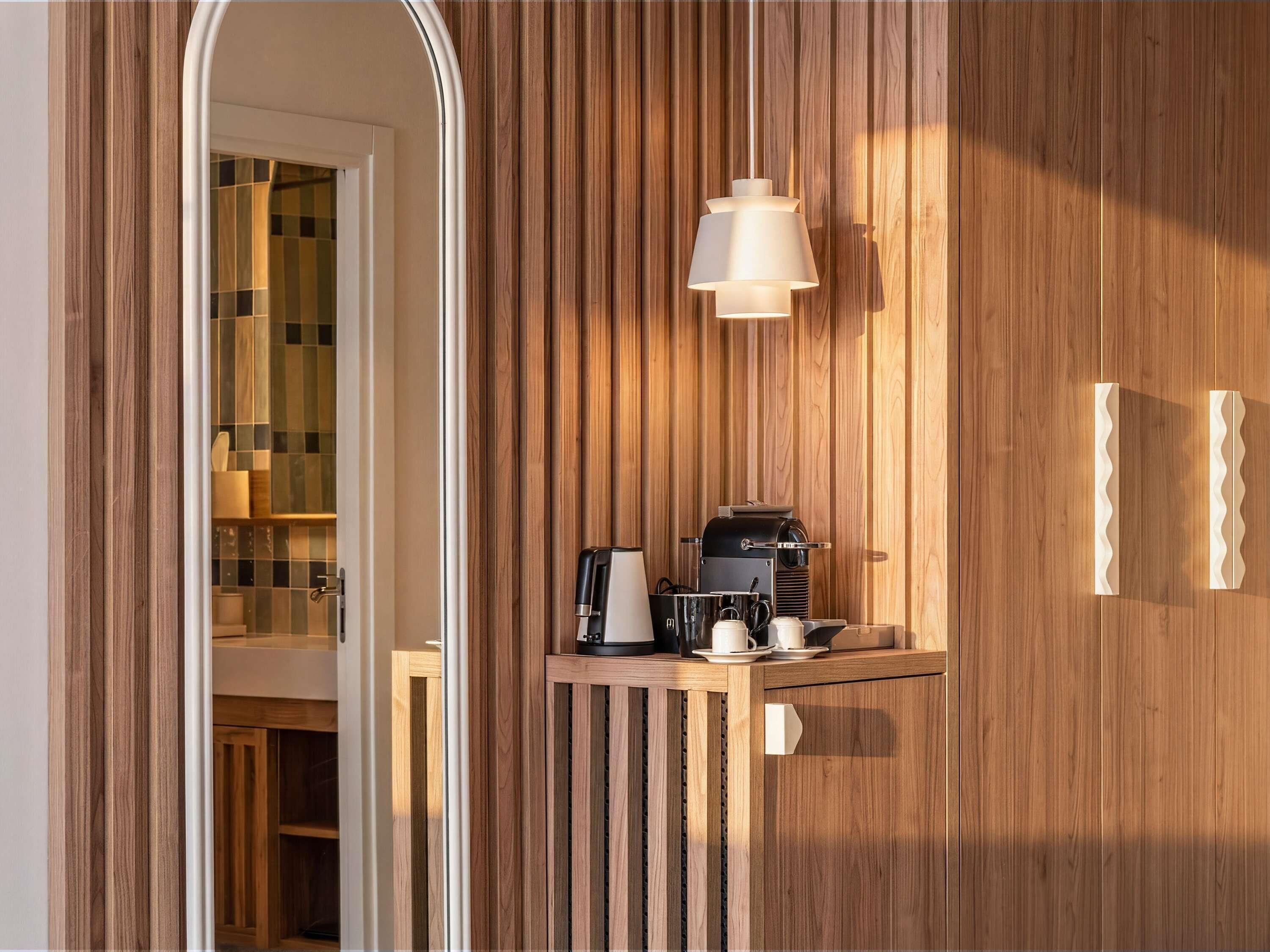 A wooden wall with a built-in shelf holding a coffee maker, cups, and a kettle.