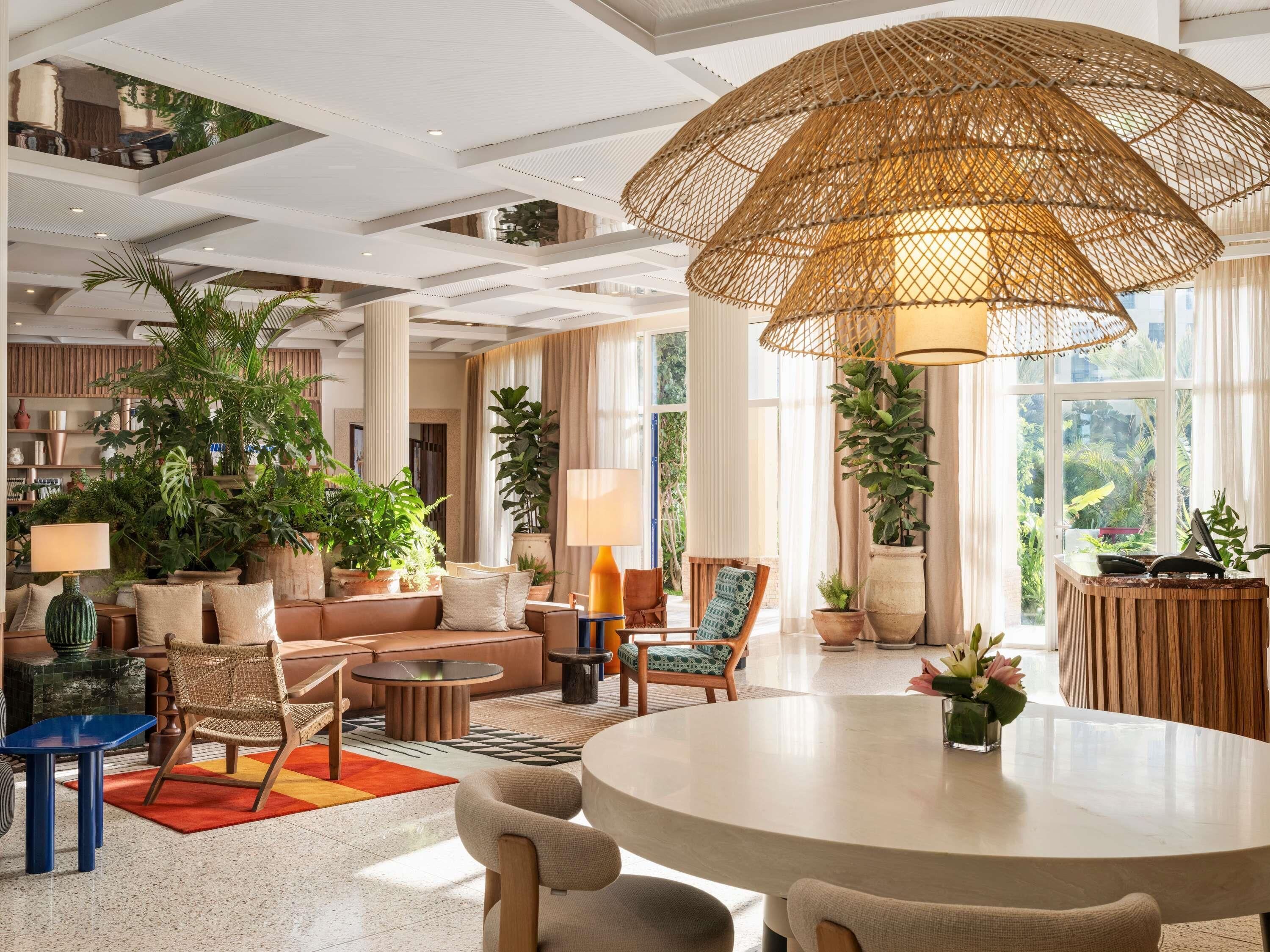 A spacious living area with a round table, comfortable seating, and a large woven ceiling light fixture.