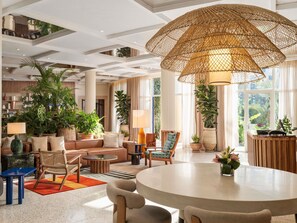 A spacious living area with a round table, comfortable seating, and a large woven ceiling light fixture. - Le Médina Essaouira Thalassa Sea  & Spa - MGallery Collection (Essaouira)