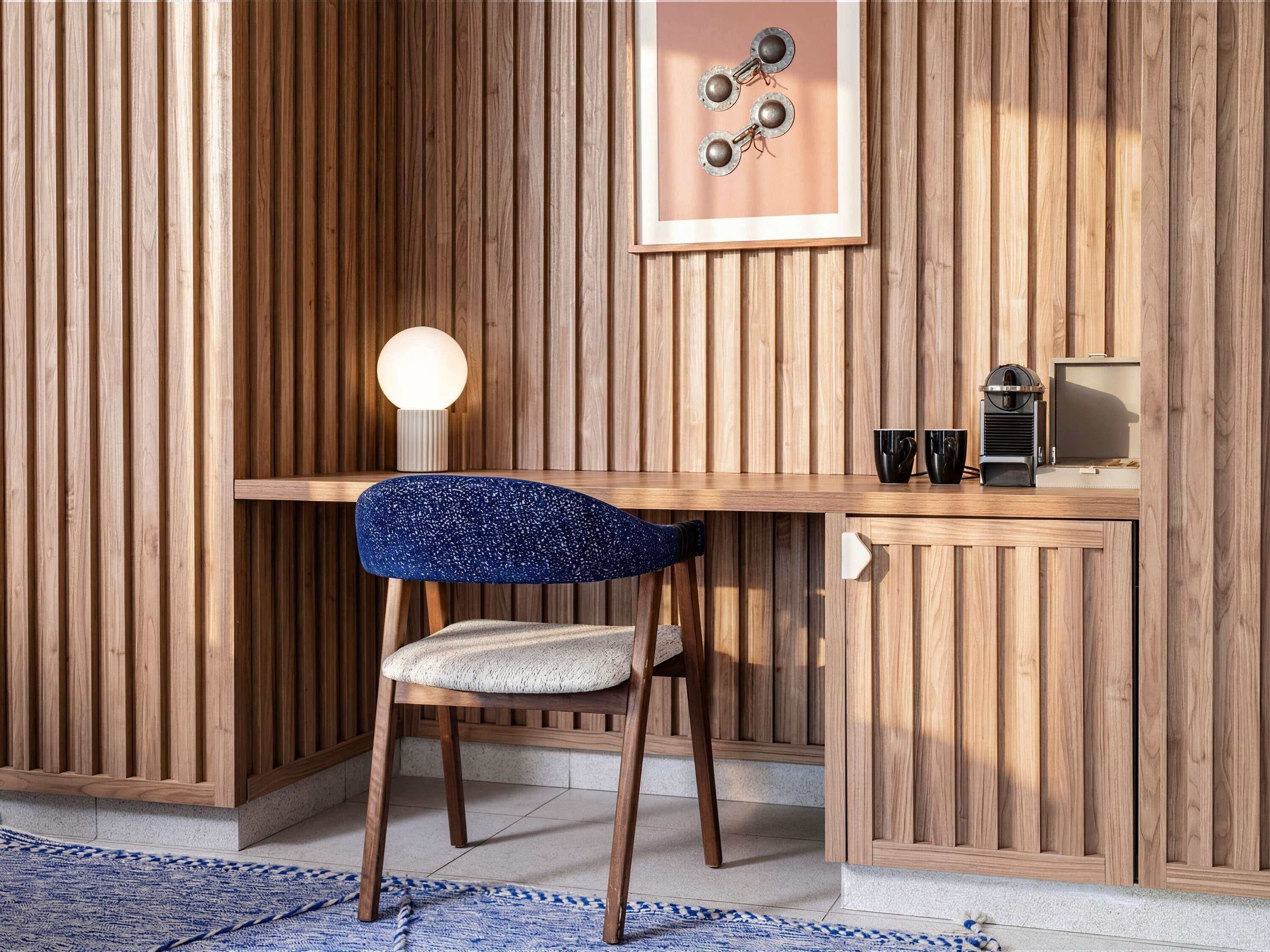 Una habitación con paneles de madera, un escritorio, una silla y un cuadro en la pared.