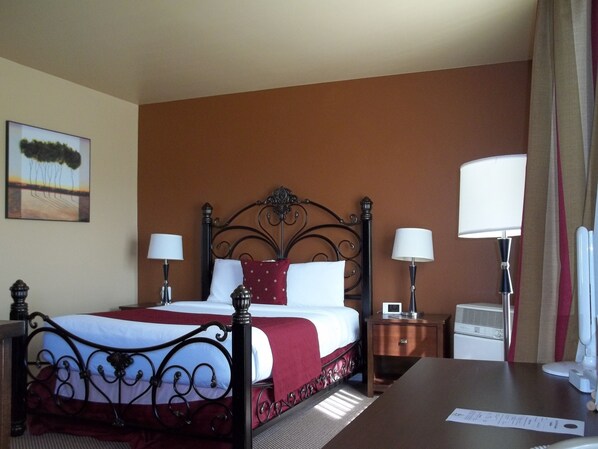 A hotel room with a bed, two bedside tables, a desk, and a lamp.