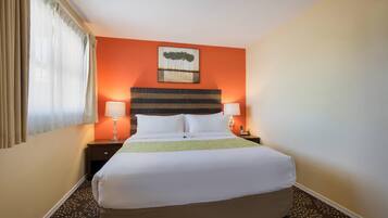 A hotel room with a large bed, two bedside tables, a lamp on each table, and a painting on the wall.