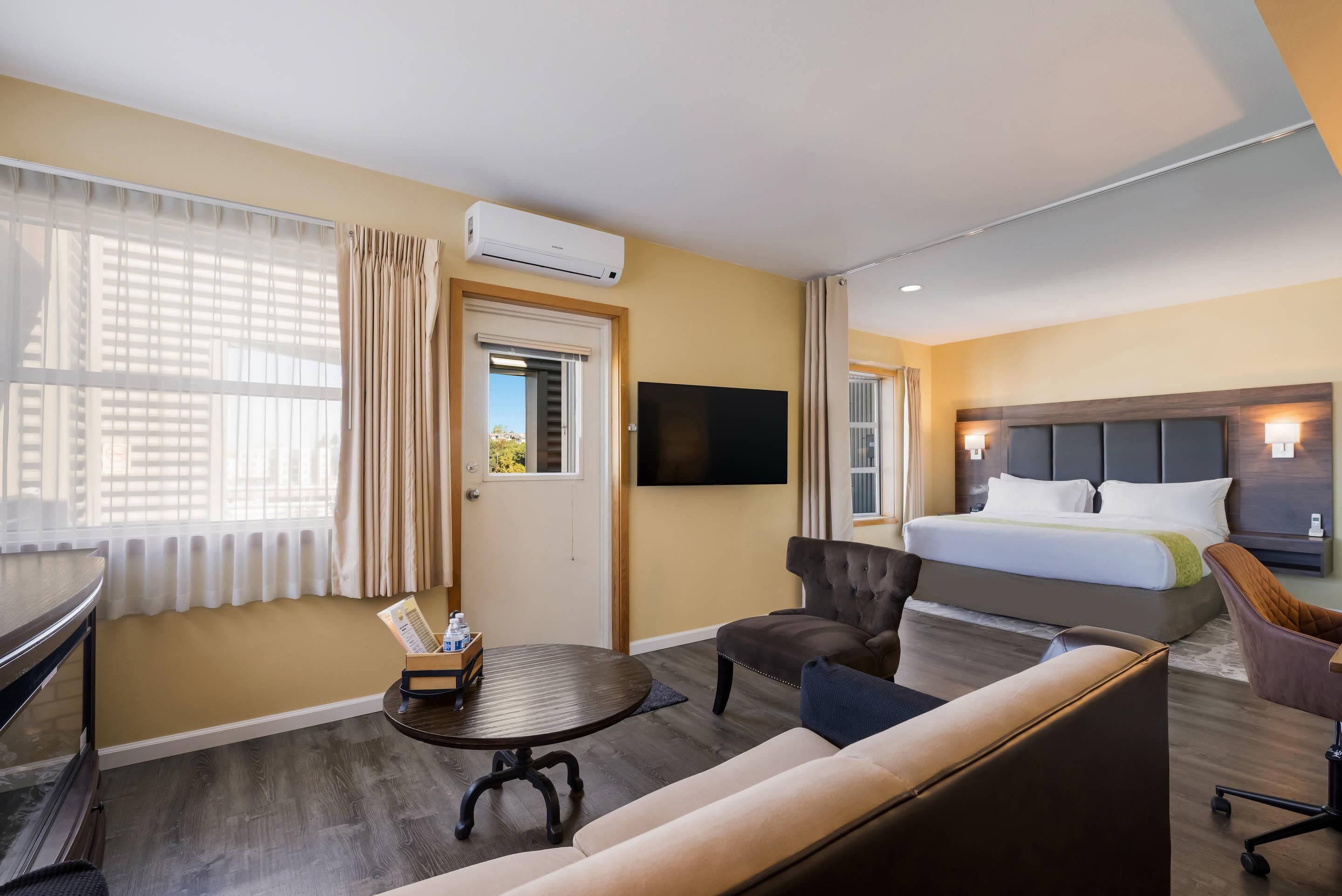A hotel room with a bed, a sofa, a TV, and a desk with a chair.