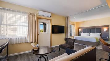Una camera d'albergo con un letto, un divano, una televisione e una scrivania con una sedia.