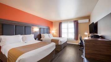 Ein Hotelzimmer mit zwei Betten, einem Schreibtisch und einem Fernseher.