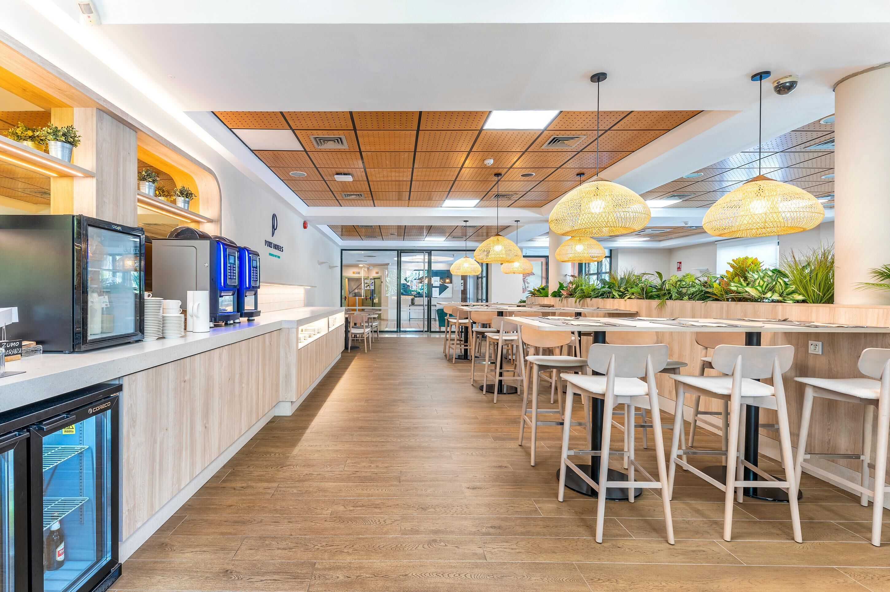 A modern cafe with a long counter, bar stools, and a refrigerator.