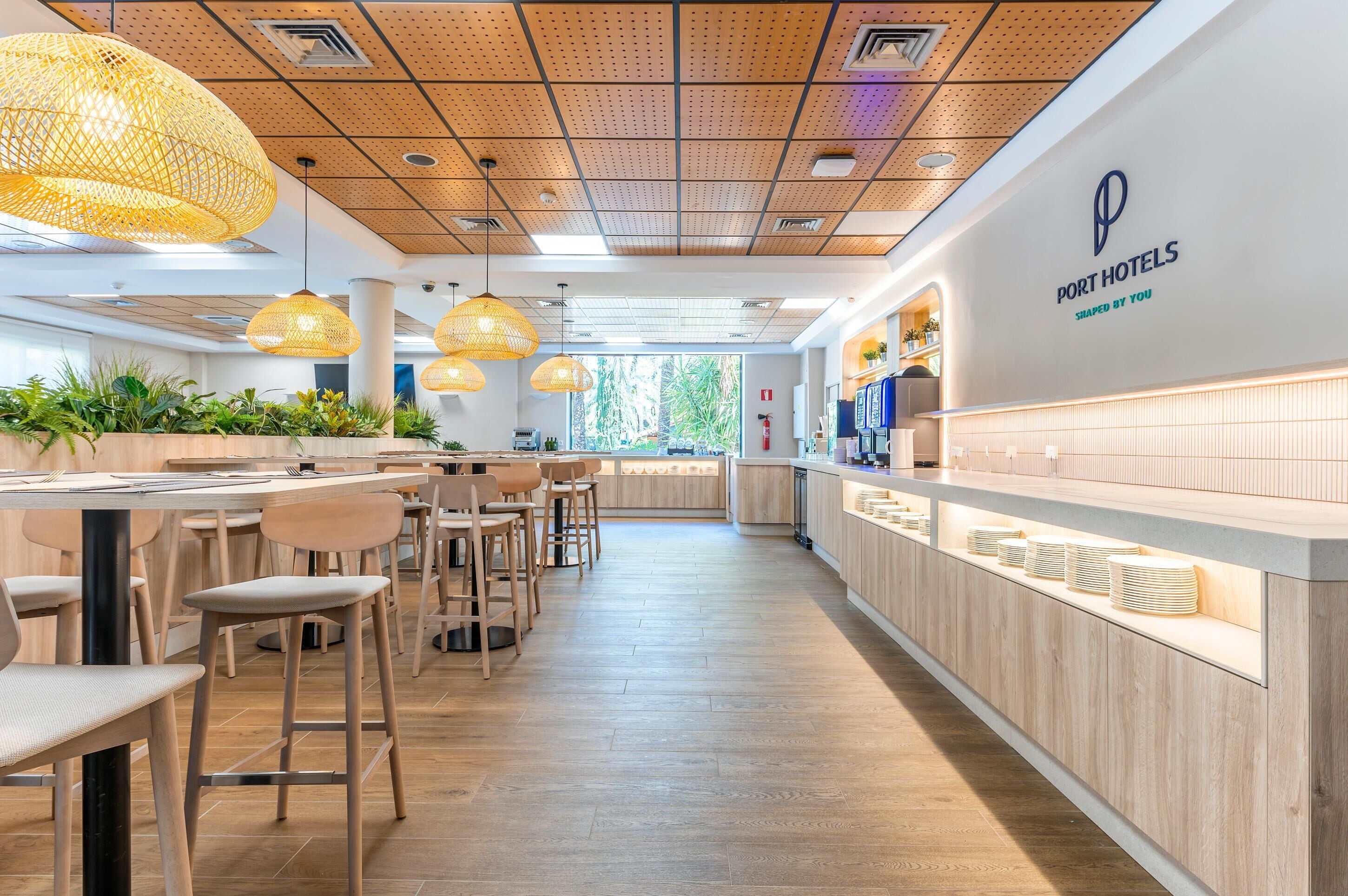 A modern hotel lobby with wooden flooring, a reception desk, and hanging wicker lamps.