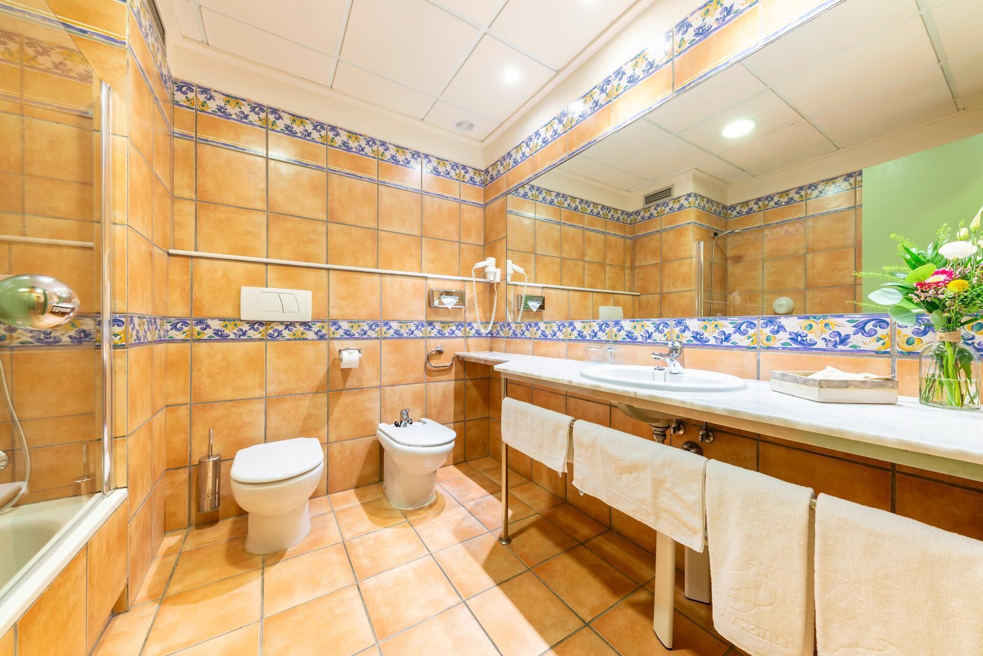 Un bagno con una vasca, due servizi igienici, un lavandino e uno specchio.