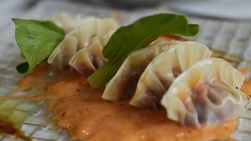 Un plato de dumplings con salsa y hojas de albahaca.