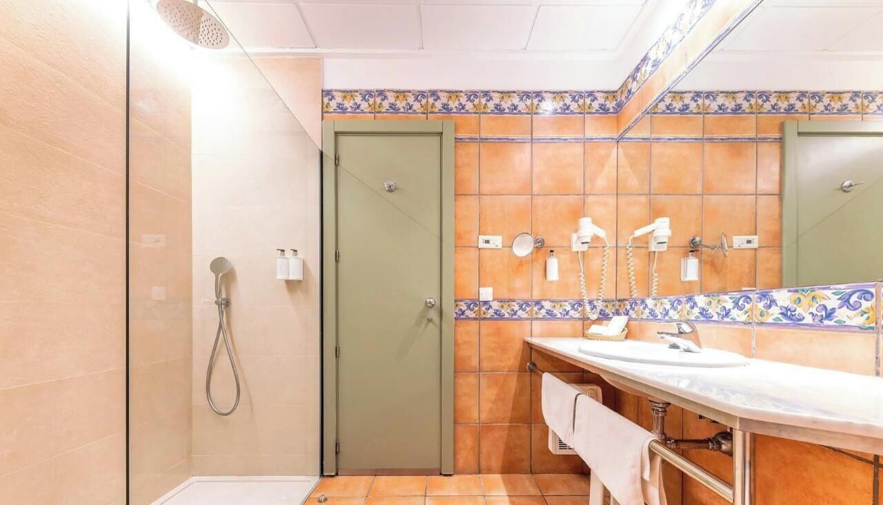 Un baño con ducha, lavamanos y espejo.