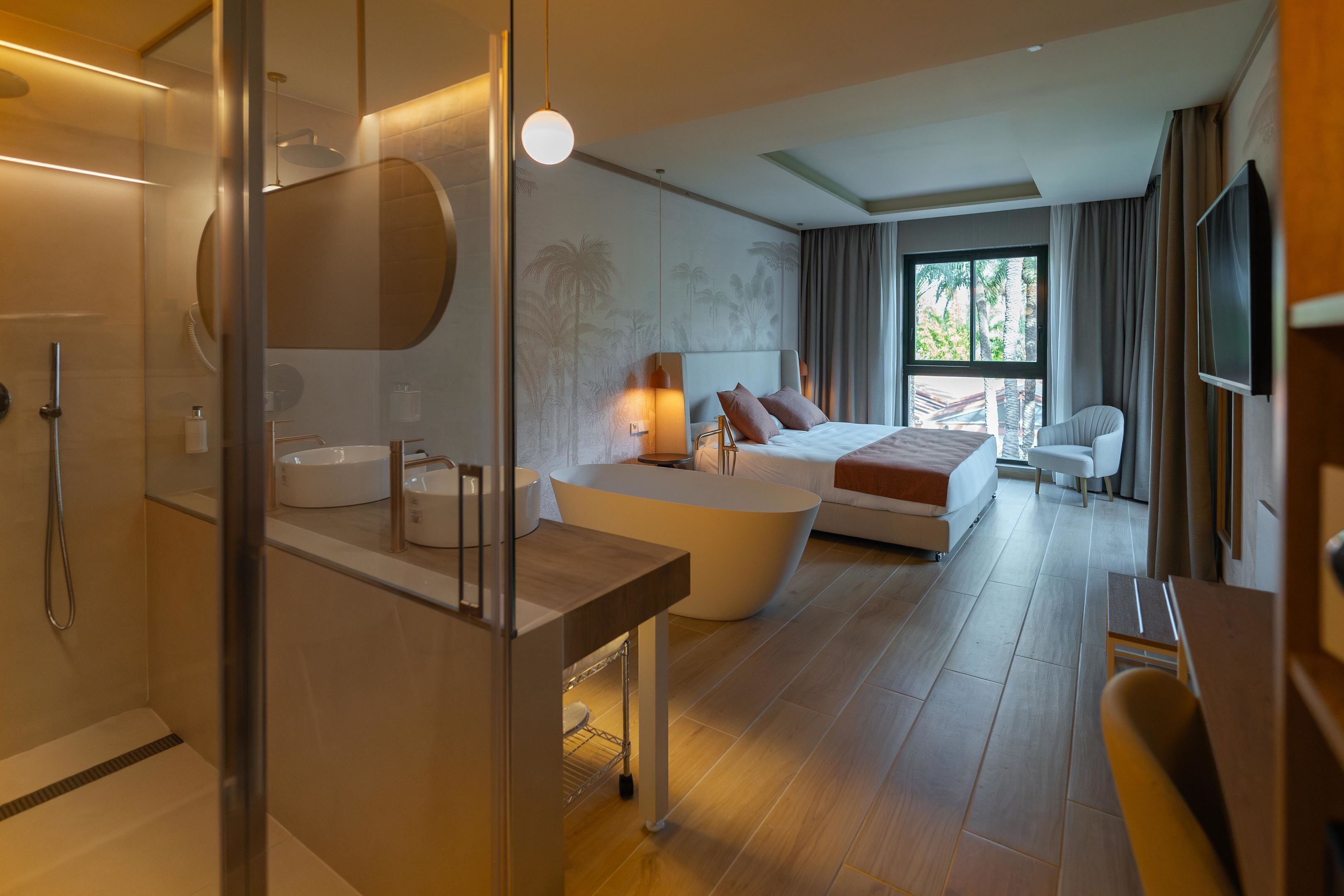 Una habitación de hotel moderna con una cama grande, un área de descanso, una bañera y un televisor.