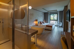 Una habitación de hotel moderna con una cama grande, un área de descanso, una bañera y un televisor.