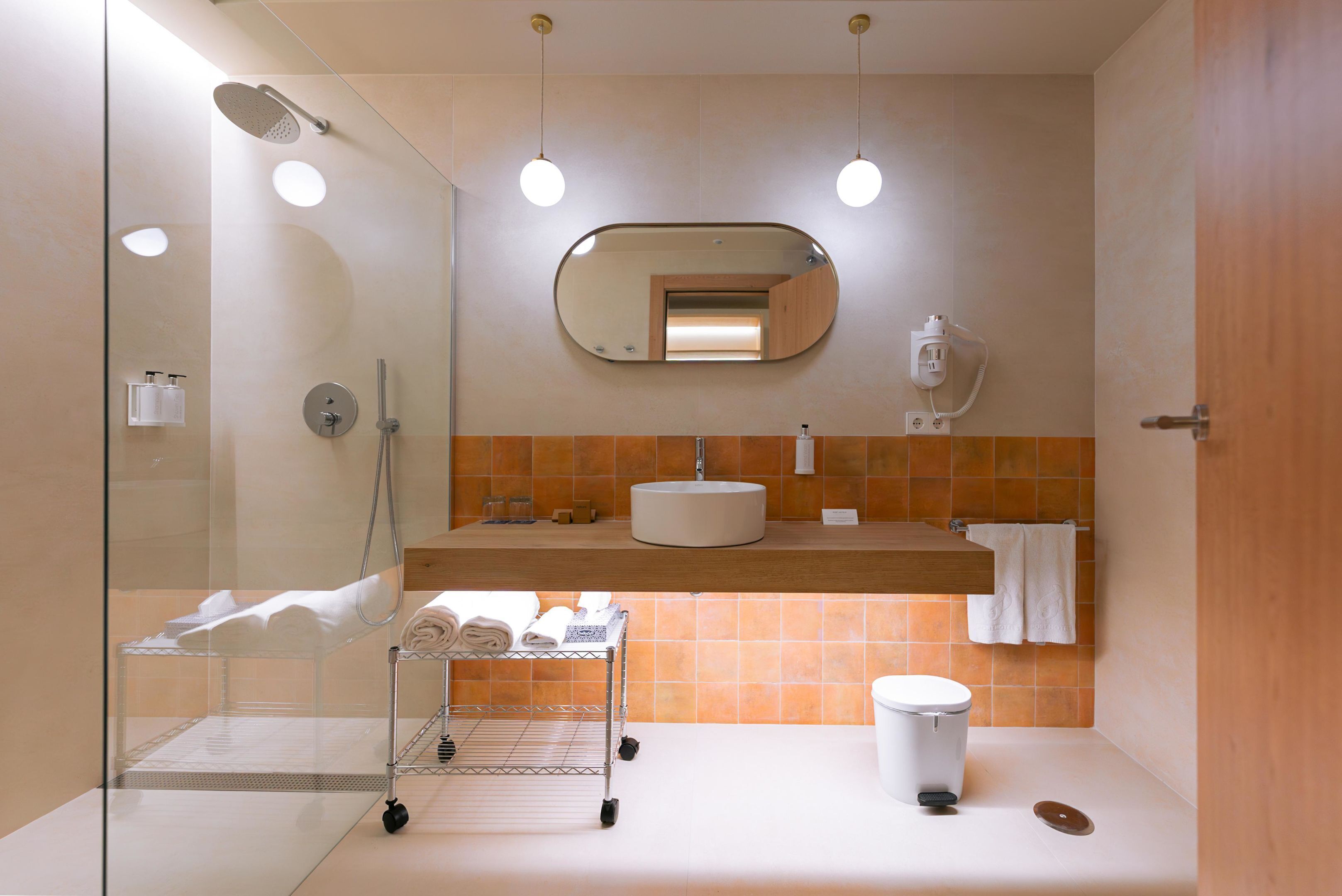 Een moderne badkamer met een douchecabine van glas, een wastafel met spiegel erboven en een handdoekrek.