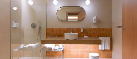 Un baño moderno con cabina de ducha de vidrio, un lavamanos con espejo y un perchero para toallas.