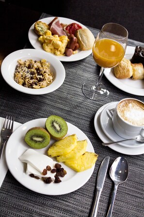 Un desayuno con platos de comida, un vaso de zumo de naranja y una taza de café.