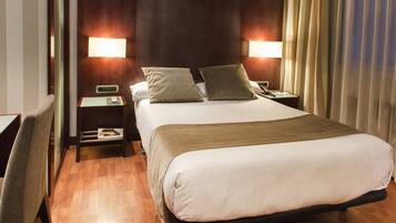 A hotel room with a large bed, two bedside tables, a chair, and a nightstand.