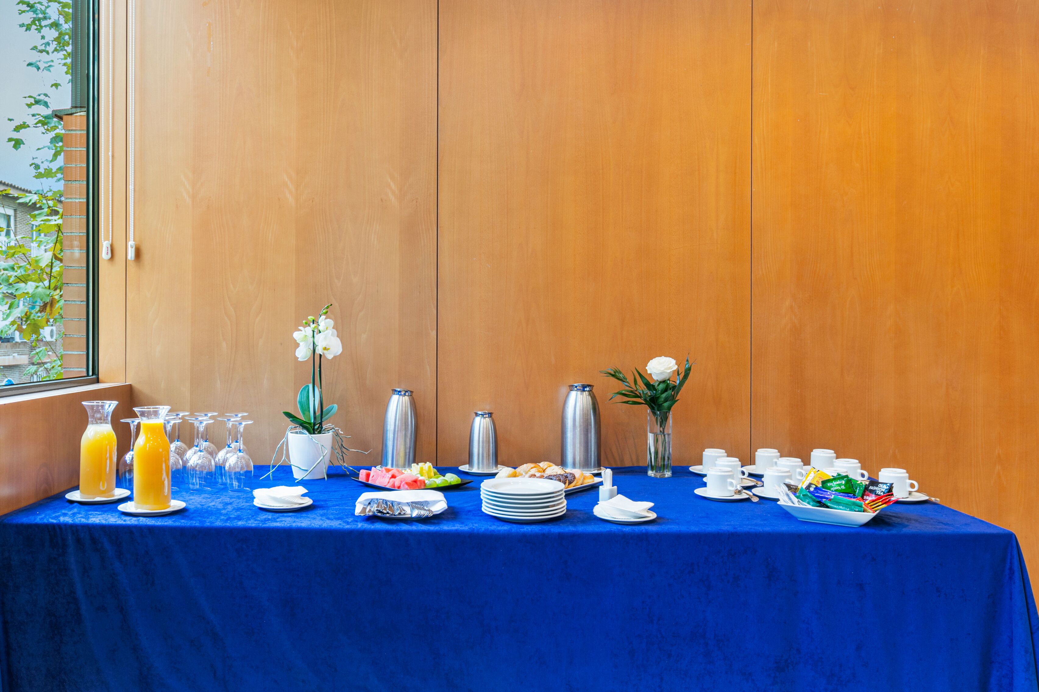 A breakfast buffet table with various food items, drinks, and utensils.