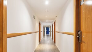 A long, narrow hallway with wooden handrails on both sides, leading to a blue door at the end. - Sercotel de los Reyes (San Sebastian de los Reyes)