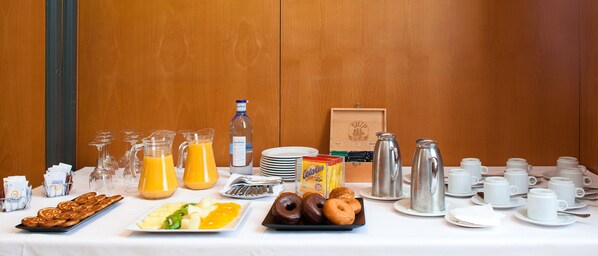 Un bufé de desayuno con distintos alimentos, bebidas y vajilla.