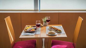 Una mesa de comedor con dos platos de comida, dos copas de vino y una pequeña planta.