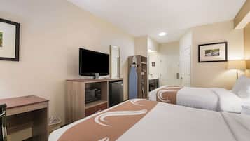 A hotel room with two beds, a desk with a television, a microwave, and a small refrigerator.