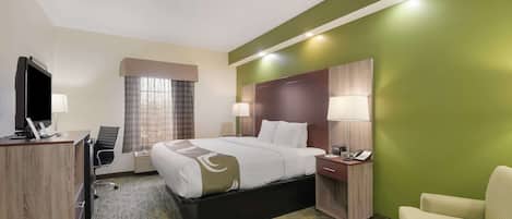 A hotel room with a bed, desk, chair, and a television.