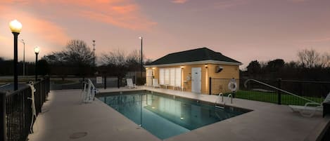 Une piscine entourée d’une maison en arrière-plan, d’une clôture et d’un poste de surveillance pour les sauveteurs.