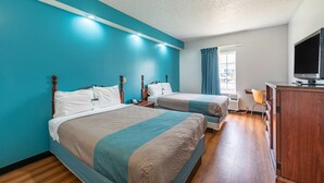 Habitación de hotel con dos camas, televisión, escritorio y ventana con cortinas.