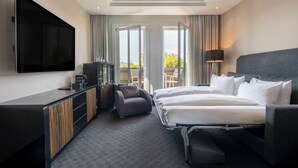 A hotel room with a bed, a desk, a chair, a TV, and a balcony with curtains. - Hotel NEWBERLIN (Berlin)
