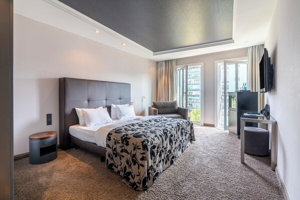 A modern hotel room with a large bed, a desk, and a television.